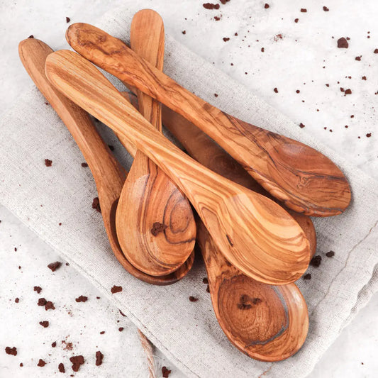 Set of wooden spoons on a textured surface with small dark particles.