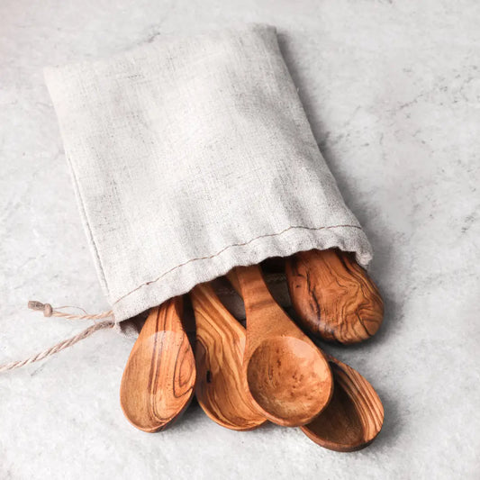 Wooden spoons in a cloth bag on a light gray surface
