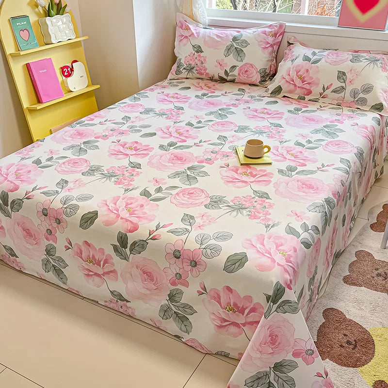 Floral bedspread on a bed with pillows and a small table in a room.